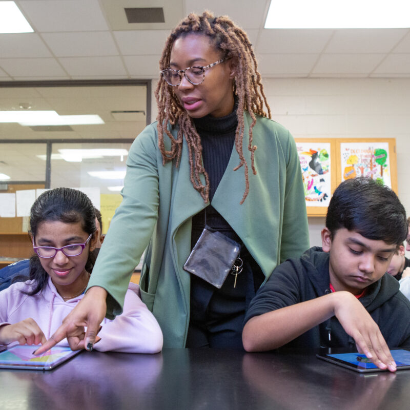 A teacher helps students during a coding lesson at Sutton Middle School.