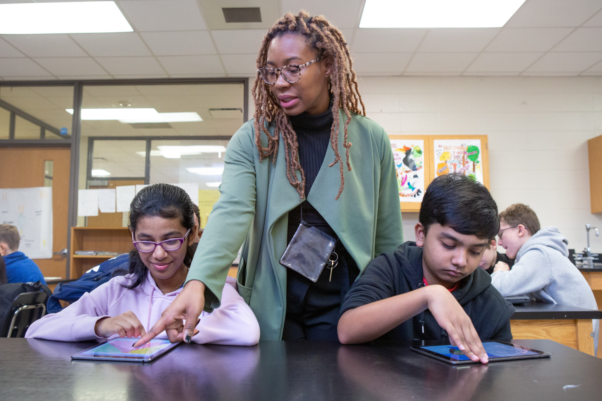 A teacher helps students during a coding lesson at Sutton Middle School.